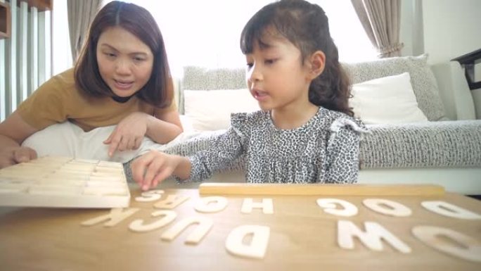 小女孩在家里的客厅和妈妈一起玩和学习字母