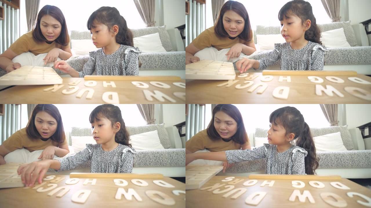 小女孩在家里的客厅和妈妈一起玩和学习字母