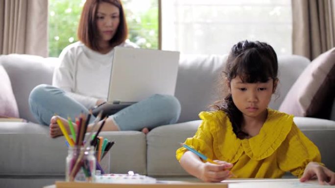 小女孩在家里的客厅与妈妈在笔记本电脑上做作业