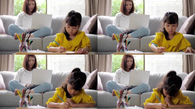 小女孩在家里的客厅与妈妈在笔记本电脑上做作业