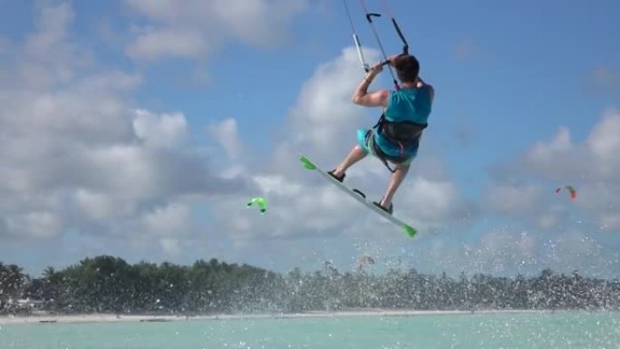 慢动作: 风筝冲浪者尝试技巧撞向绿松石海水。