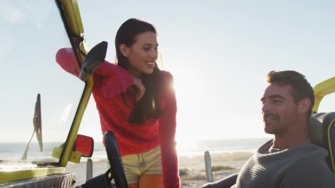 快乐的高加索女人站在坐在海边沙滩车里的男人旁边