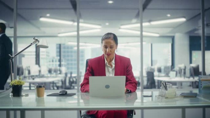 成功的白人女商人穿着完美时尚的西装，在俯瞰大城市的顶层办公室的笔记本电脑上工作。女性首席执行官管理公