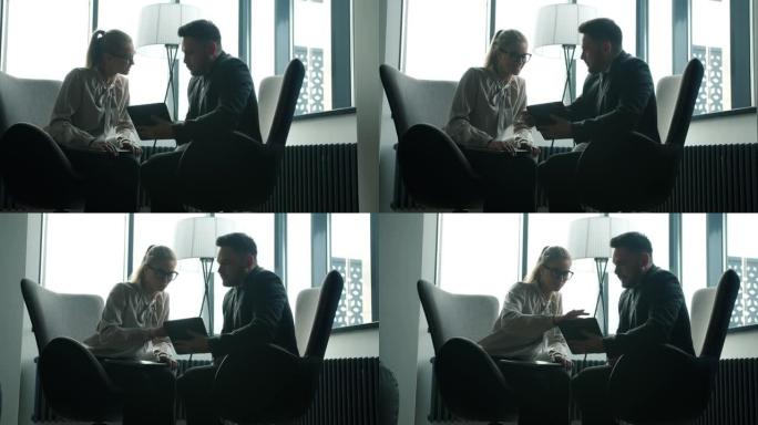 商业伙伴男女讨论项目看平板电脑屏幕在黑暗的办公室