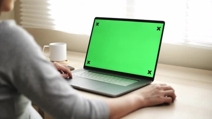 女人在家使用带绿屏显示器的笔记本电脑