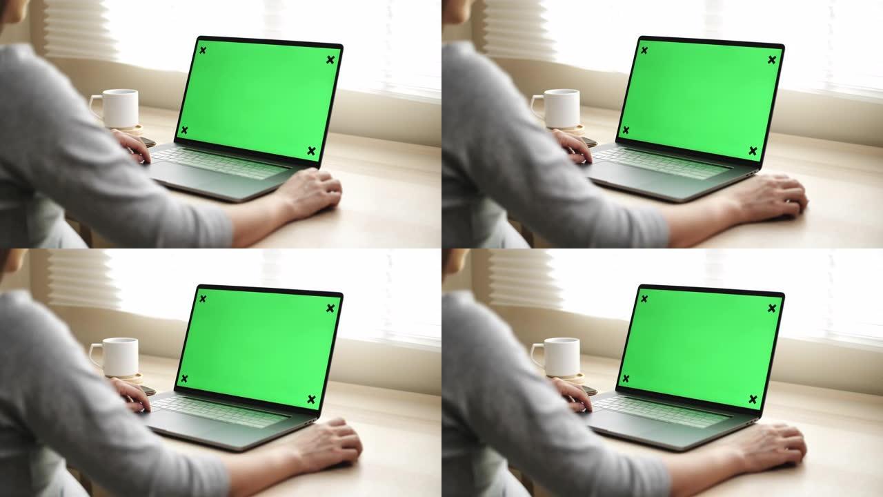 女人在家使用带绿屏显示器的笔记本电脑