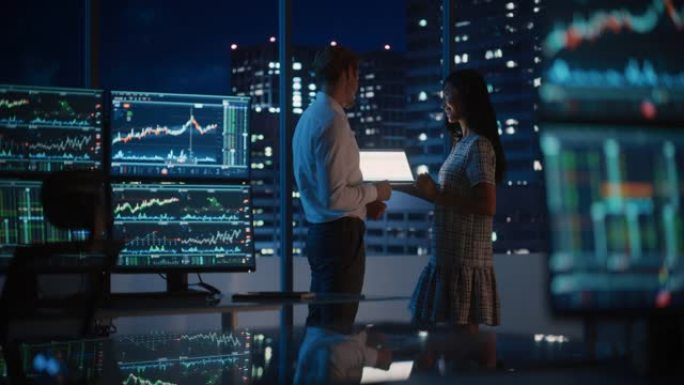 金融分析师在深夜工作时与投资银行家交谈。在平板电脑上聊天实时股票图表数据。商人在经纪机构市办公室开会