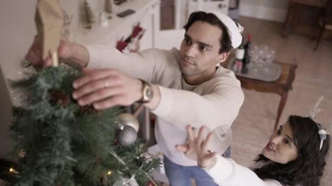 一对年轻夫妇在家里装饰圣诞树的4k录像