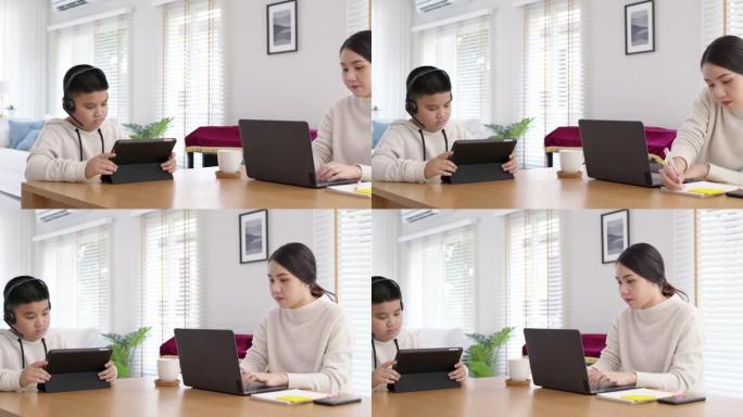 亚洲家庭母亲和孩子在家工作，桌子上放着平板电脑。