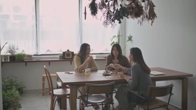 3位享受下午茶的中国女性朋友在周末休闲时间与彼此在咖啡馆分享甜点