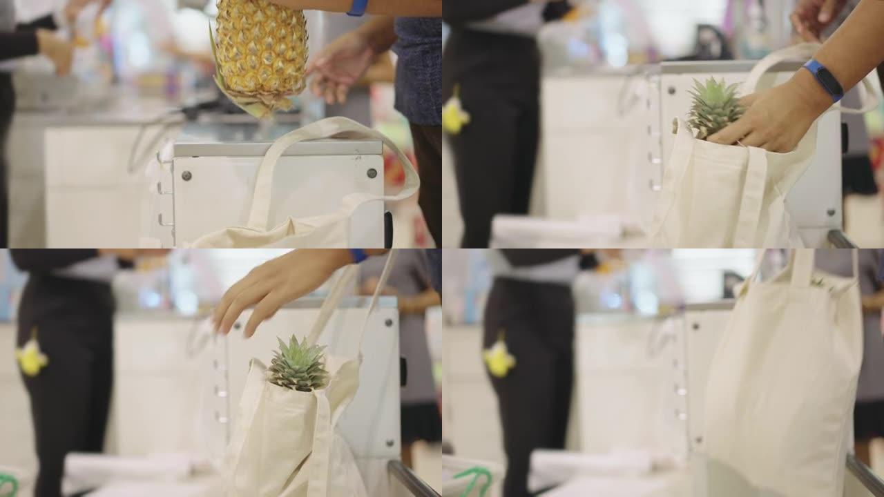 男子在结帐时将菠萝放入布购物袋中