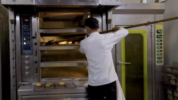 拉丁美洲面包师用木铲将面包从烤箱中取出