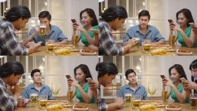 跟踪镜头: 年轻迷人的亚洲男子喝啤酒时，朋友沉迷于手机上的社交媒体而忽略聚会晚宴，感到不快乐孤独。青