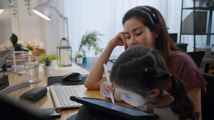 在线孕妇影响者妇女教第一个孩子女儿使用数字平板电脑在家玩集成平板电脑活动。母亲爱孩子。