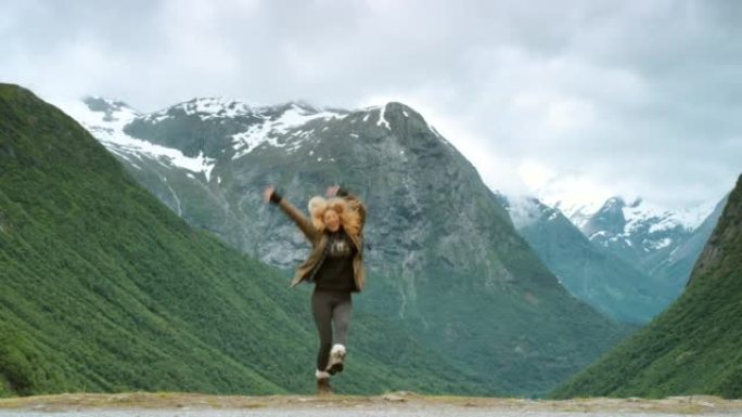 4k视频片段，一名年轻女子在Stryn探索山脉时兴奋地跳跃