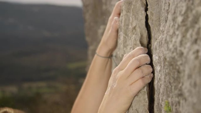 特写: 运动女子在攀岩时用粉笔举起的手抓住裂缝