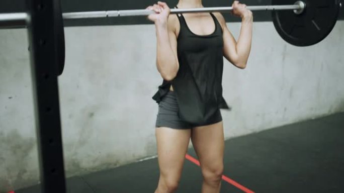 4k视频片段，一名年轻女子在健身房用杠铃进行头顶按压