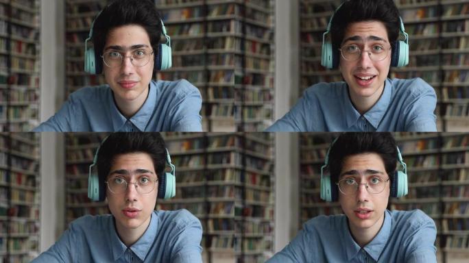屏幕肖像男远程学生戴着耳机通过网络摄像机交谈