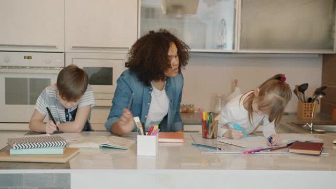 小学生男孩和女孩在家与友好的混血保姆一起做作业学习