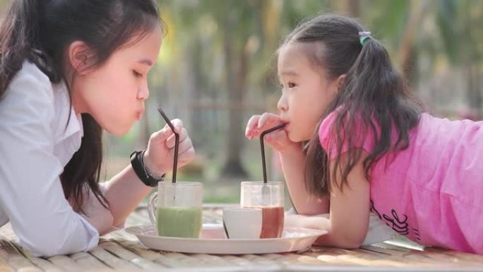 亚洲儿童女孩在公园喝果汁
