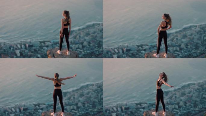 站在山顶庆祝成就的独立女人悬崖边看着日落美景享受旅行冒险