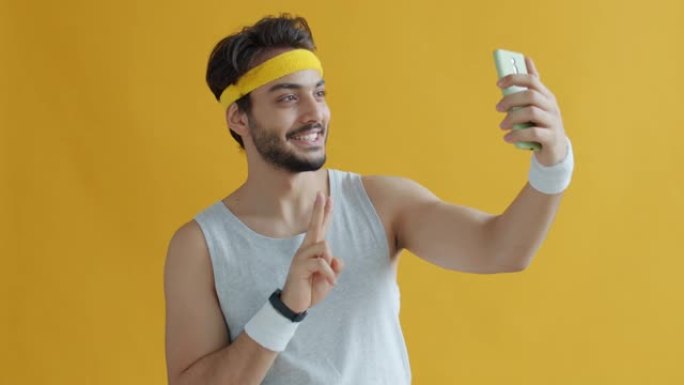 英俊的阿拉伯运动员为智能手机相机摆姿势自拍的肖像