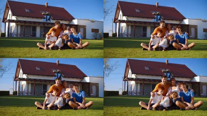 SLO MO充满爱心的家庭和三个孩子在独立屋的绿色草坪上摆姿势