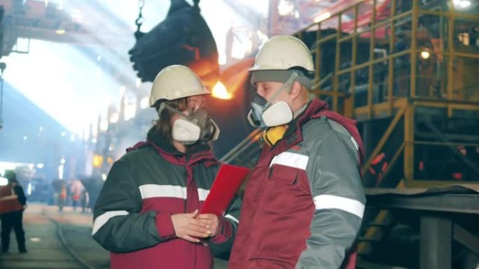 一个戴着呼吸器的男人和一个女人在钢铁厂聊天