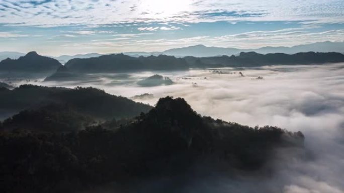 美丽的鸟瞰图雾随着日出在山上的雨林上滚动