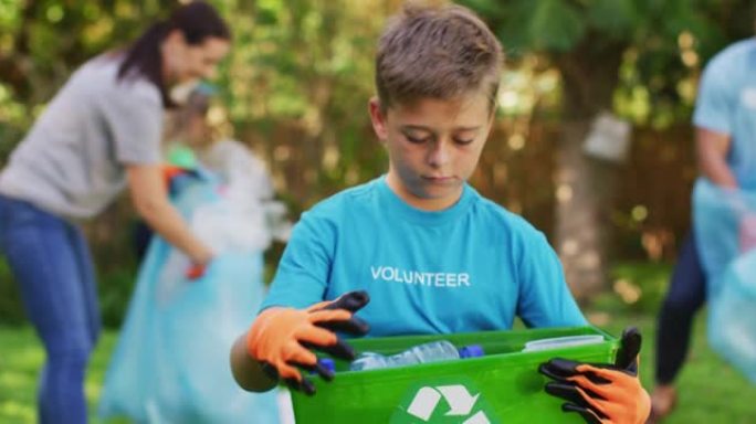 微笑的高加索儿子在户外拿着回收板条箱，与父母一起收集塑料垃圾