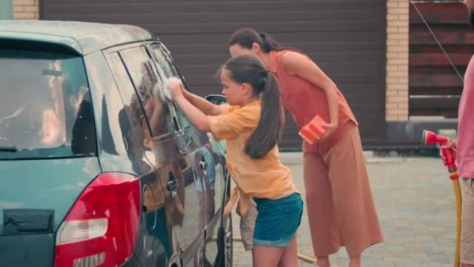 可爱的孩子在夏天给父母洗车