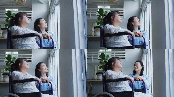 微笑的亚洲女医生望着窗外，与坐在轮椅上的女病人交谈