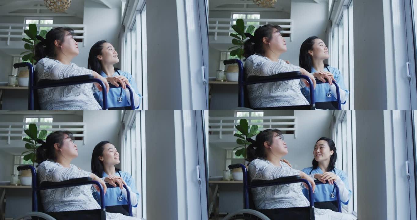 微笑的亚洲女医生望着窗外，与坐在轮椅上的女病人交谈