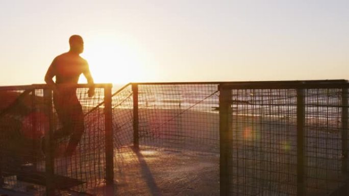 专注的非裔美国人在楼梯上奔跑，在日落时分在海边户外锻炼