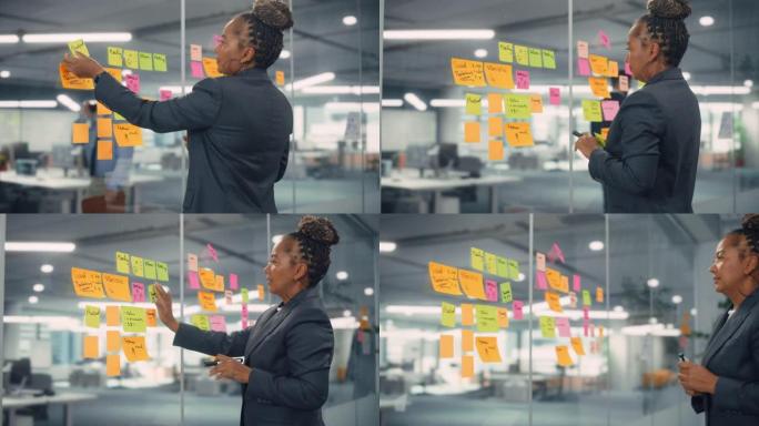 非裔美国女商人用纸质笔记在办公室墙上创建项目计划。时尚自信的经理，从事商业、金融和营销项目。多元化团