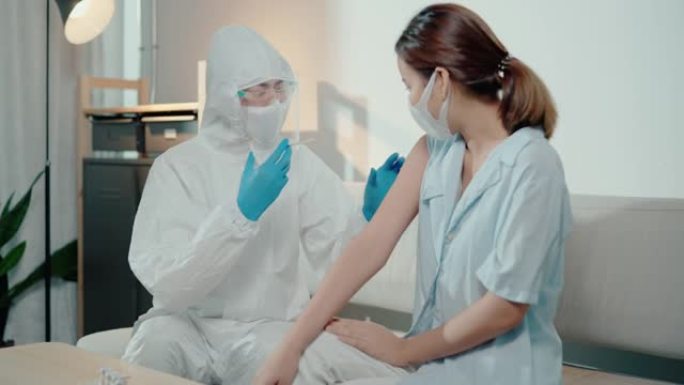 穿着防护工作服的医生在家注射冠状病毒疫苗。