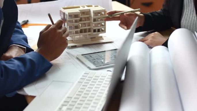 建筑师和同事团队在办公室的建筑模型上进行构建