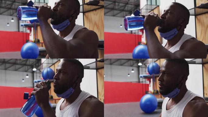 非裔美国男子戴着降低的面罩在健身房喝酒