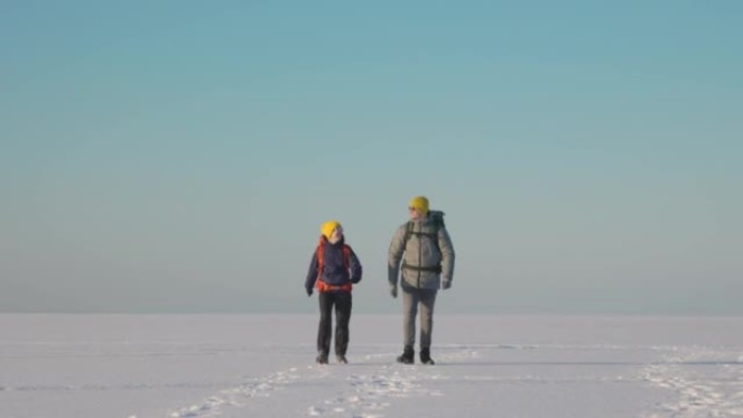 两个背着背包的旅行者穿过雪场。慢动作