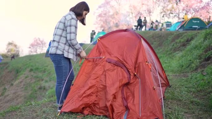 女旅行者在山上的露营地搭建帐篷