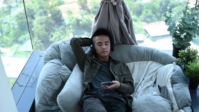 一个亚洲华裔少年男孩用耳机听音乐