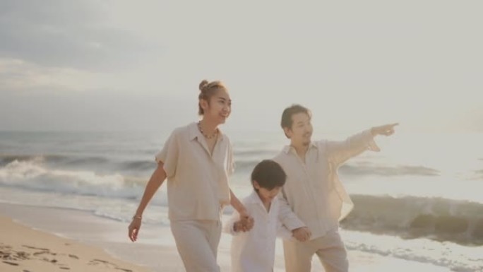 亚洲家庭牵着手在日落时沿着海滩散步