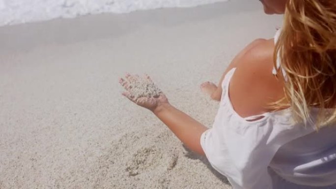 女人的手在海滩上玩沙子的景色，意大利。