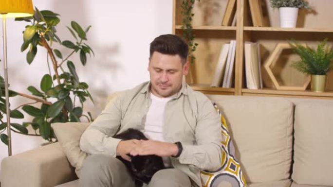 中年男子在家沙发上抚摸他的猫