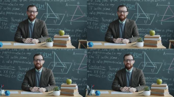 大学数学老师的慢动作肖像坐在教室的桌子上，用黑板