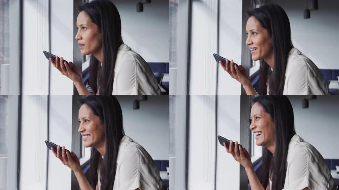 微笑的混血女商人站在办公室的智能手机上聊天