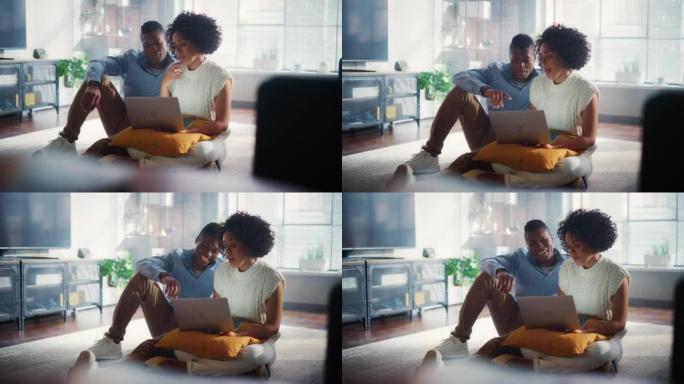 黑人夫妇坐在他们时尚的公寓的客厅地板上，使用笔记本电脑。女朋友和男朋友聊天，网上购物，选择产品在线订