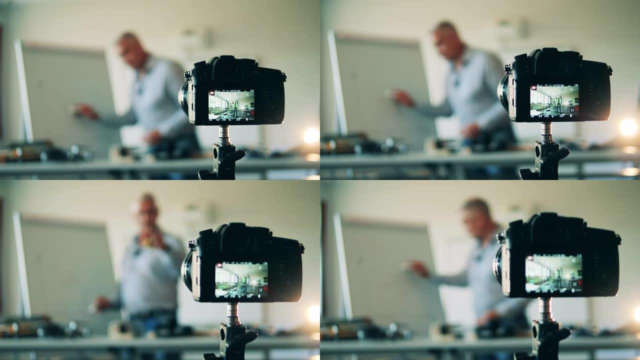 相机正在拍摄一名男老师的电子课