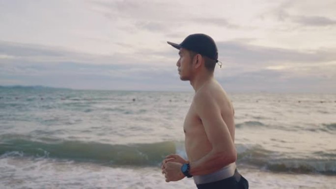 在海滩上跑步的亚洲男性。