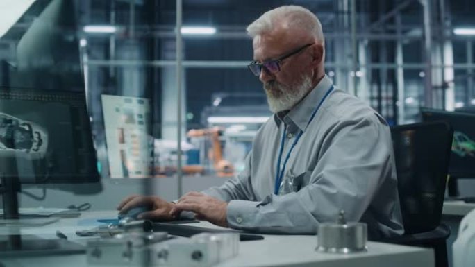 汽车厂办公室: 白人男性总工程师的肖像在自动机械臂装配线上生产高科技电动汽车的台式计算机上工作。电子